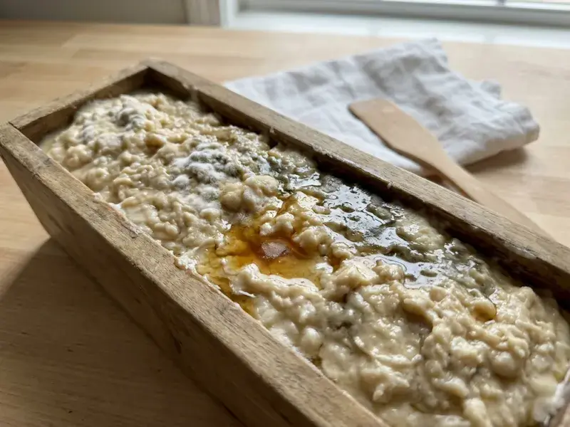 A soap mold with a layer of clear oil pooled on top of curdled-looking soap batter